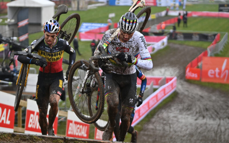Wout Van Aert et Mathieu van der Poel portent leur vélo sur le dos en montant des escaliers.